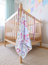 Load image into Gallery viewer, Crib with a colorful baby blanket draped over the side in a nursery setting.
